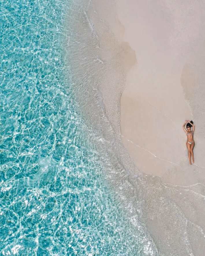 Kobieta opalająca się na piaszczystej plaży nad turkusową wodą
